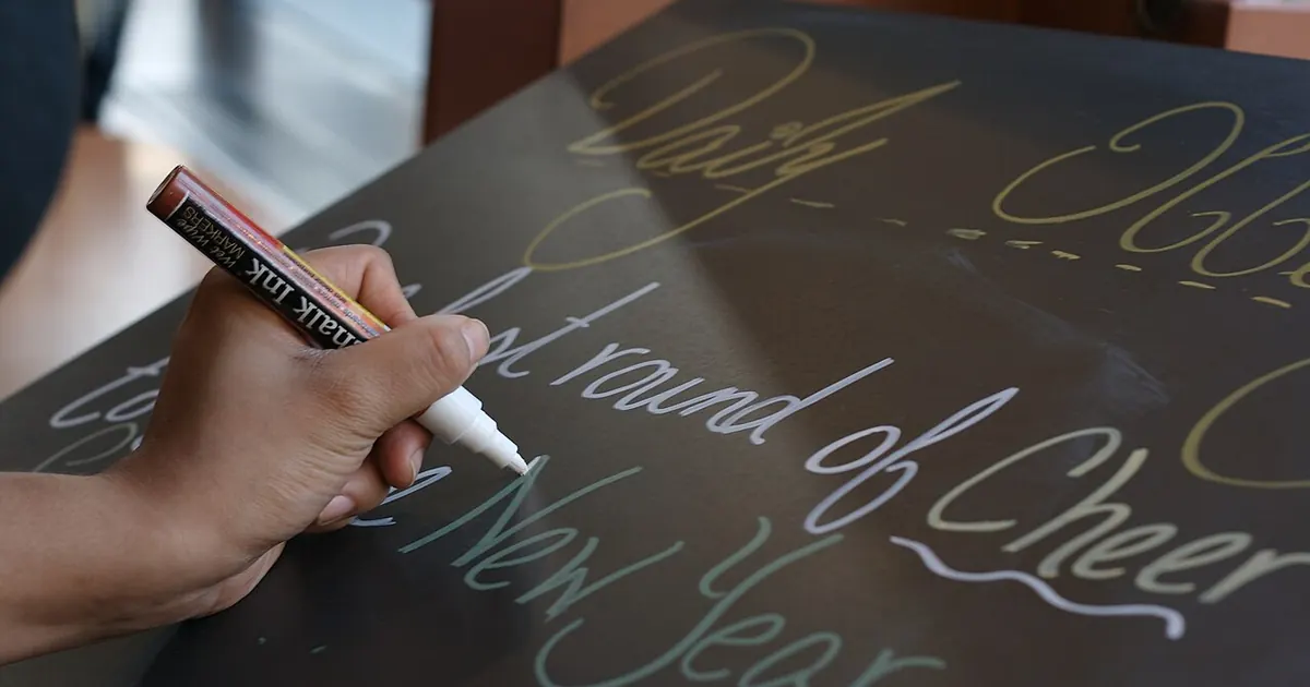 Main traçant une calligraphie sur un fond noir