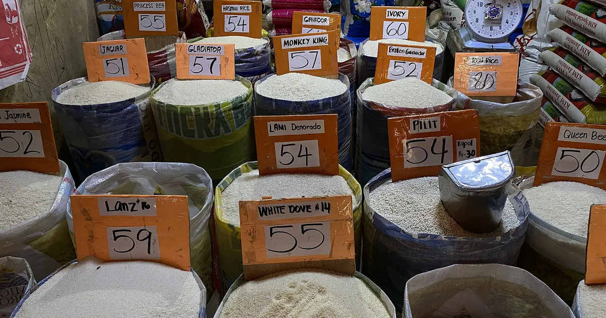 Étal de marché avec sacs de riz et prix affichés