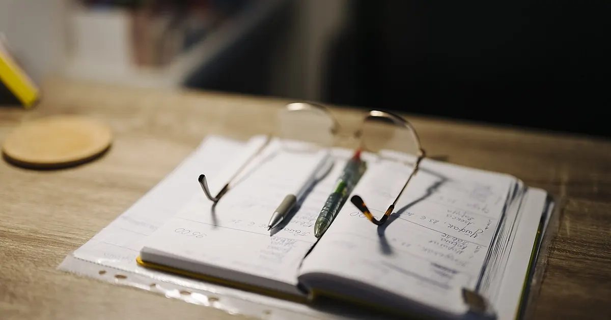 Agenda ouvert, lunettes et stylo sur un bureau